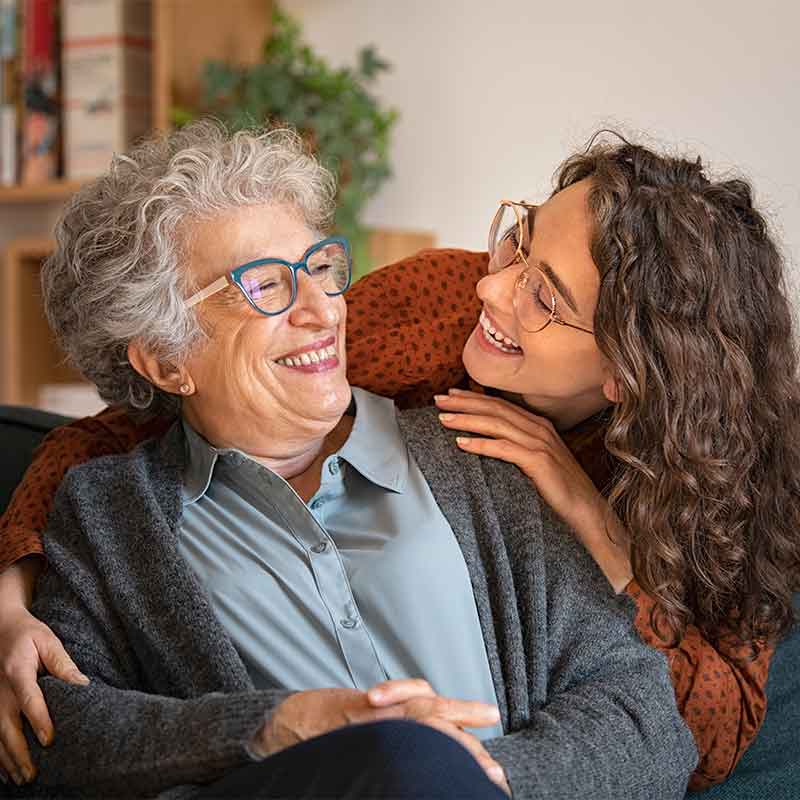 Grandmother and granddaughter laughing together in their home